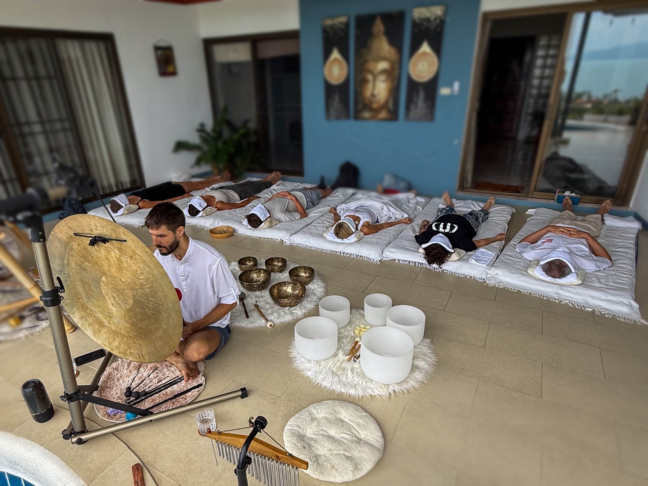 Group sound healing session with participants relaxing on mats