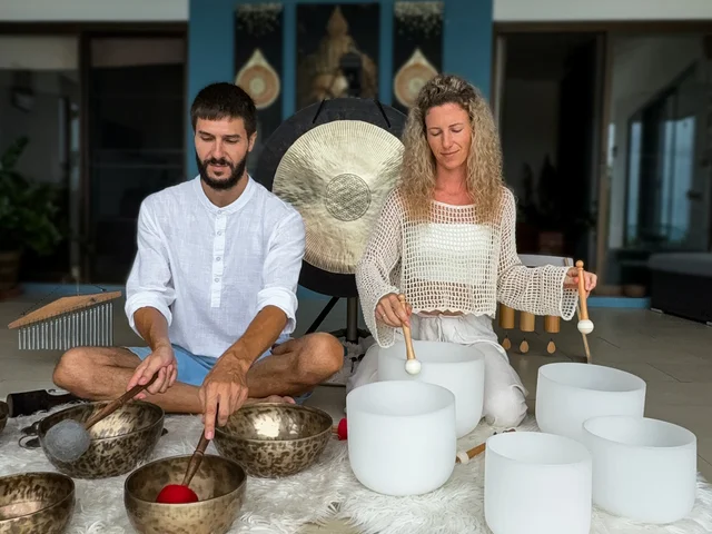 Max and Olha in their modern sound healing studio with singing bowls and gongs